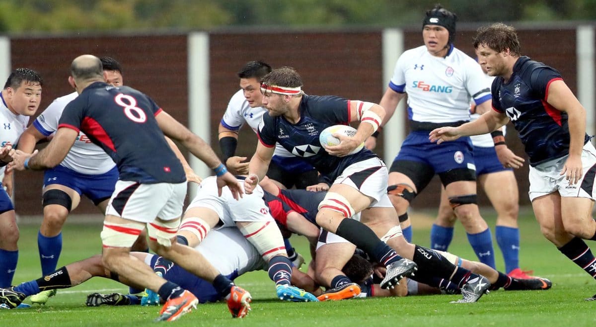 Hong Kong rugby team in action during a competitive match, player running with the ball while teammates and referee look on