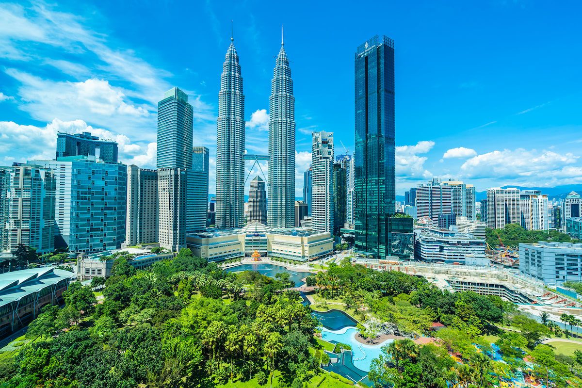 Daytime skyline of Kuala Lumpur featuring the Petronas Twin Towers and KLCC Park with lush greenery and water features