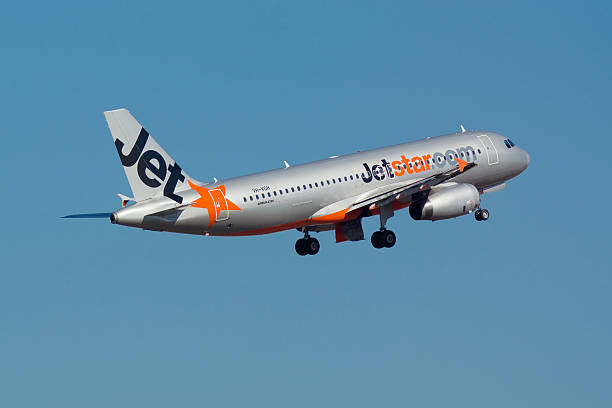 Jetstar Airways Airbus A320 aircraft taking off against a clear blue sky, featuring the airline’s signature silver fuselage and orange star logo.