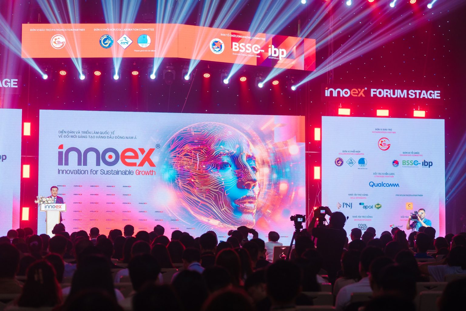 Audience attending InnoEx Southeast Asia 2024, an innovation and sustainability forum featuring futuristic AI visuals, corporate sponsors, and keynote presentations in Ho Chi Minh City.