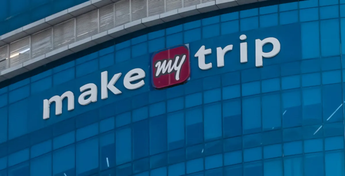 Close-up of MakeMyTrip corporate logo on the glass facade of its modern office building in India, reflecting the brand’s leadership in online travel services.