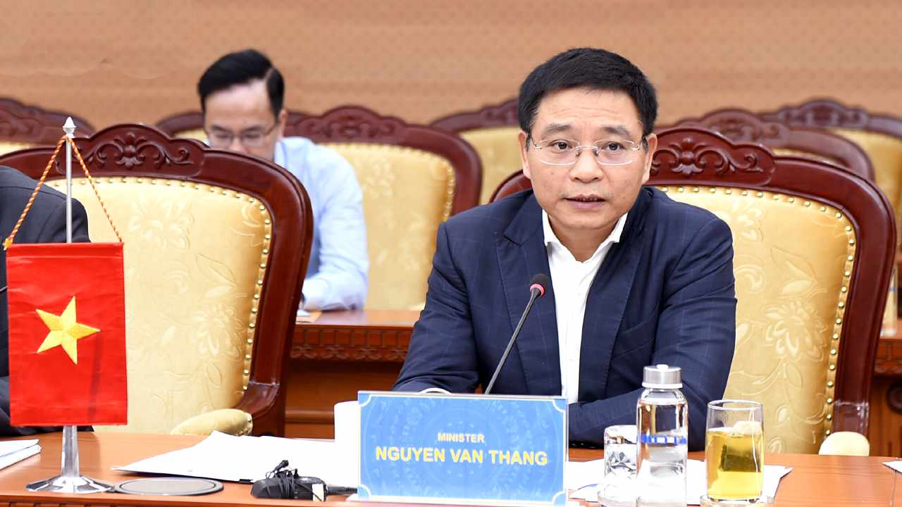 Vietnamese Minister Nguyen Van Thang speaking at an official government meeting, seated at a conference table with a microphone, national flag, and nameplate in front of him.
