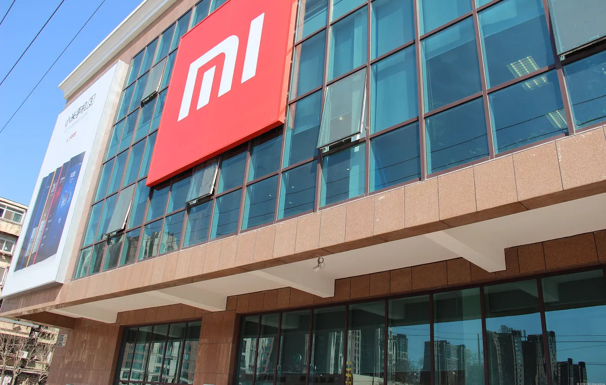 Xiaomi corporate office with large red MI logo and glass facade, showcasing the company’s branding and modern headquarters design.