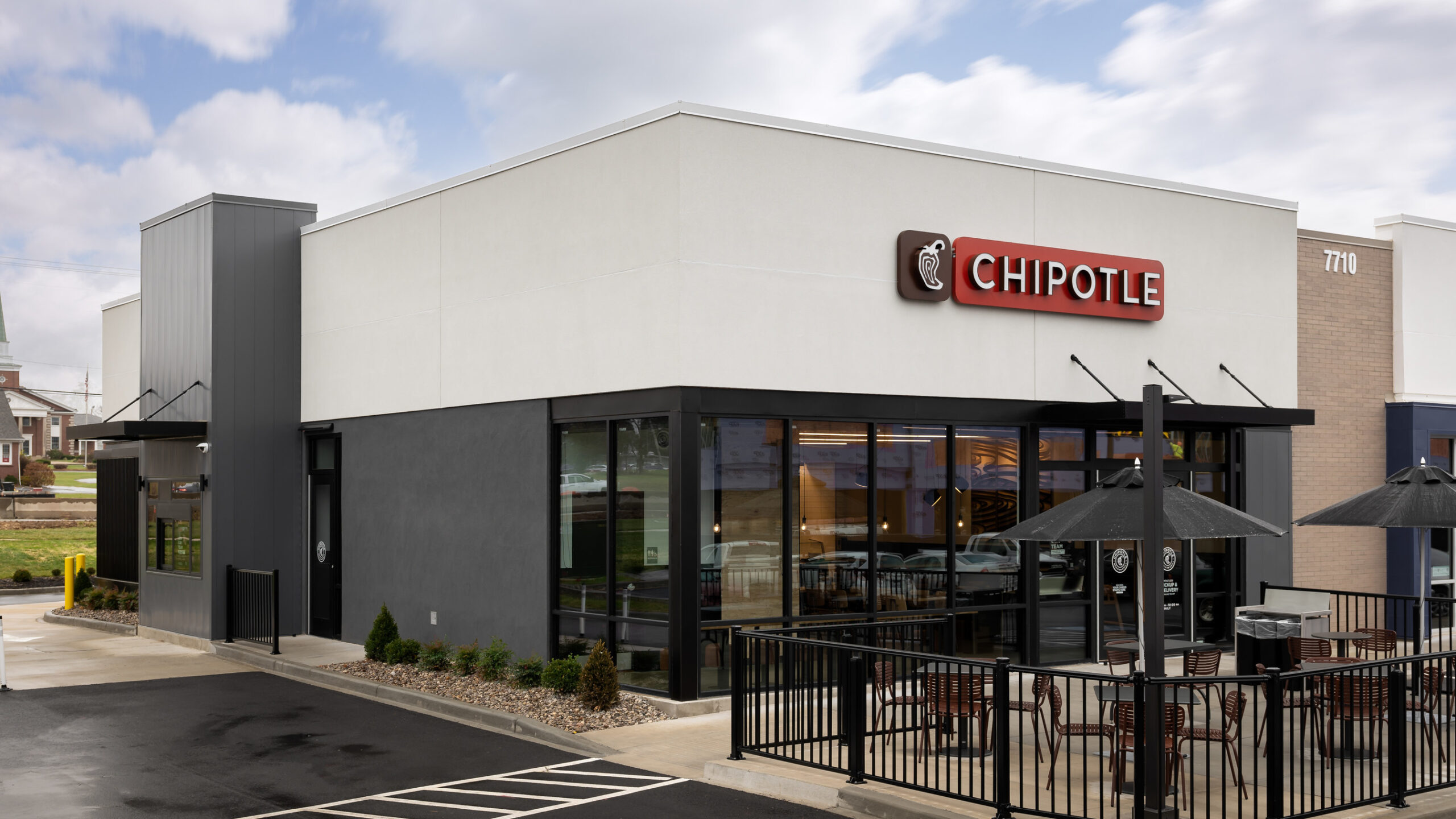 Modern Chipotle Mexican Grill restaurant exterior with patio seating and drive-thru service.