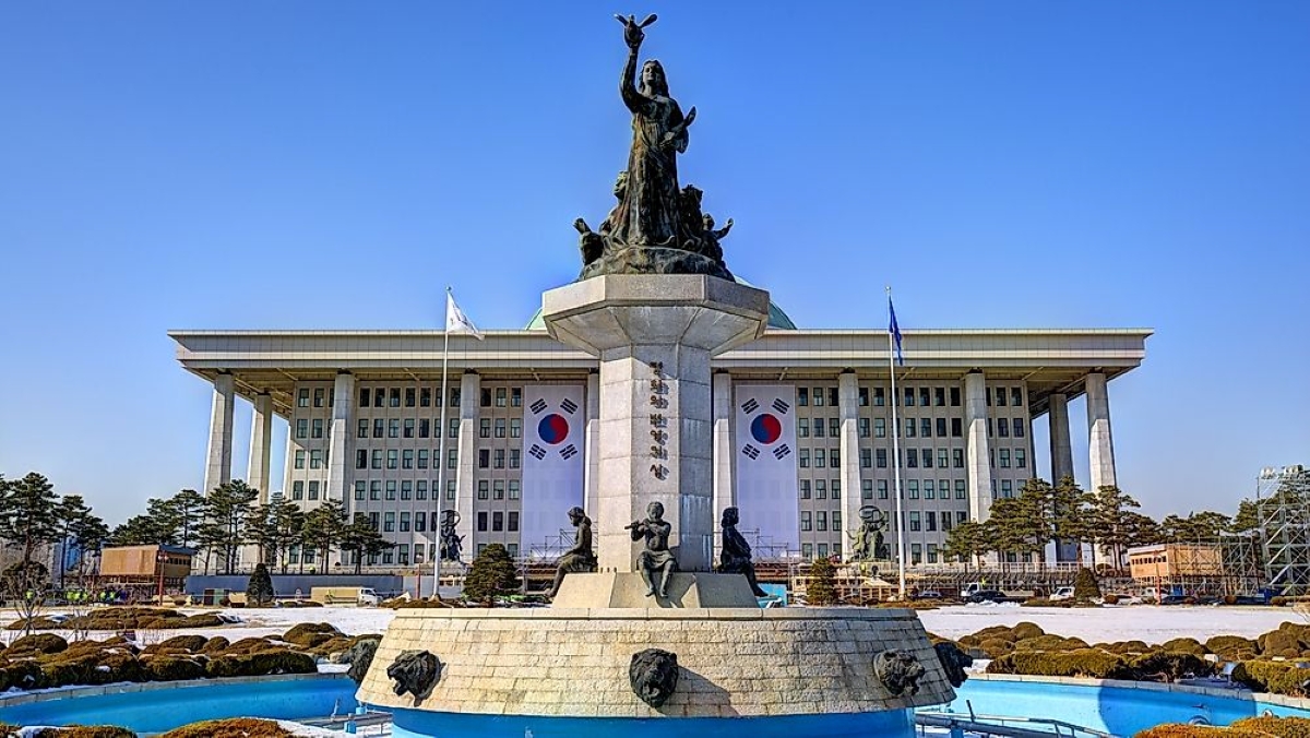 South Korea National Assembly building in Seoul with statue and South Korean flags displayed on the facade.