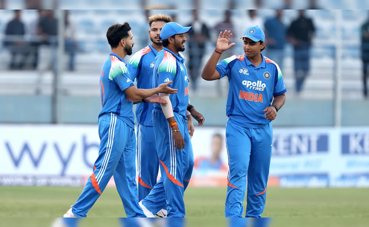 Indian men’s cricket team players celebrate during a match, wearing blue jerseys with Apollo Tyres branding, showcasing teamwork and sportsmanship on the field.