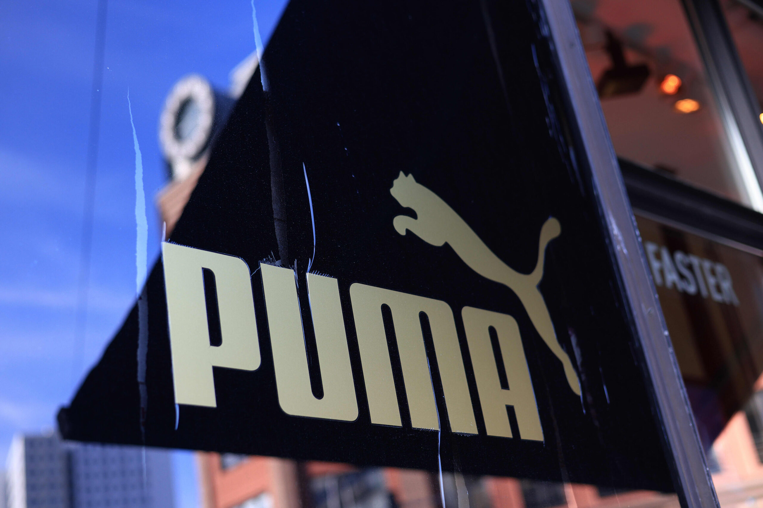 Close-up of Puma storefront sign featuring the Puma logo and bold “PUMA” lettering on a black facade.