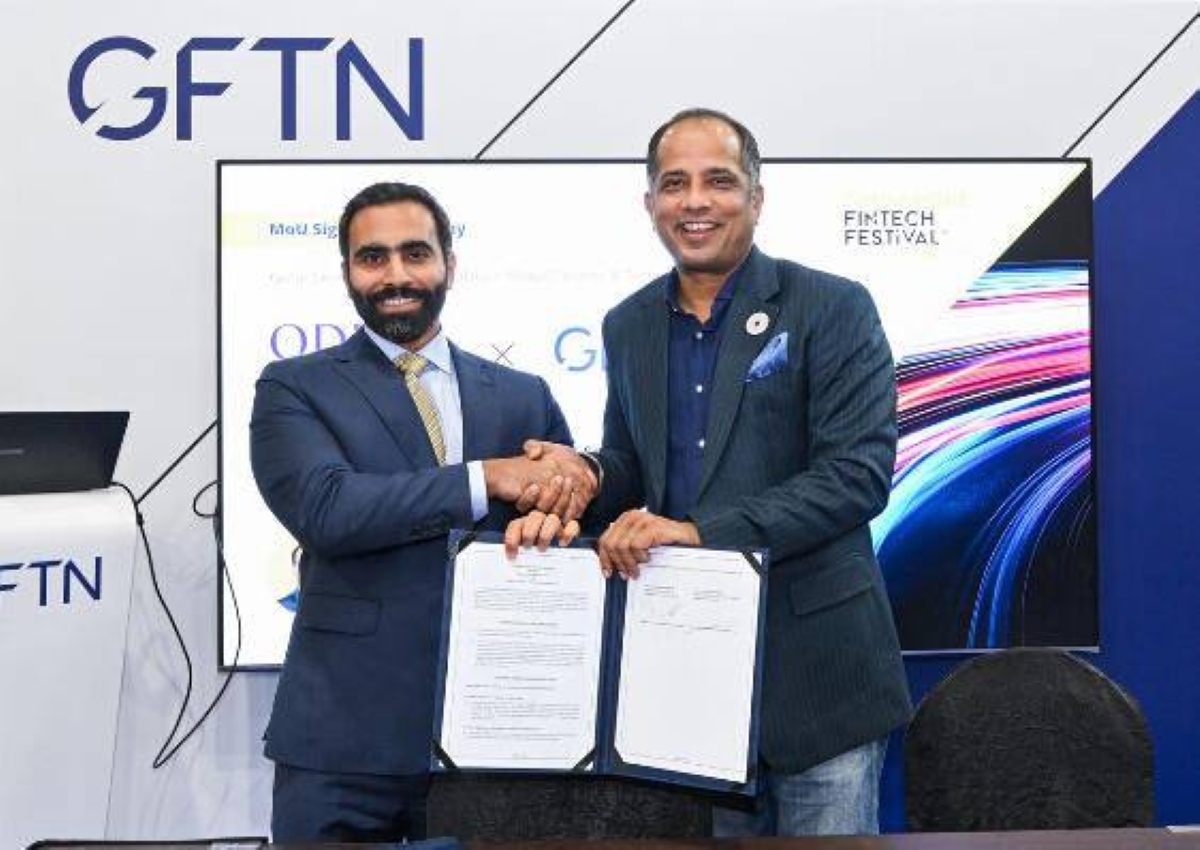 Fintech partnership announcement as two representatives exchange a handshake and present signed documents at the GFTN FinTech Festival event.