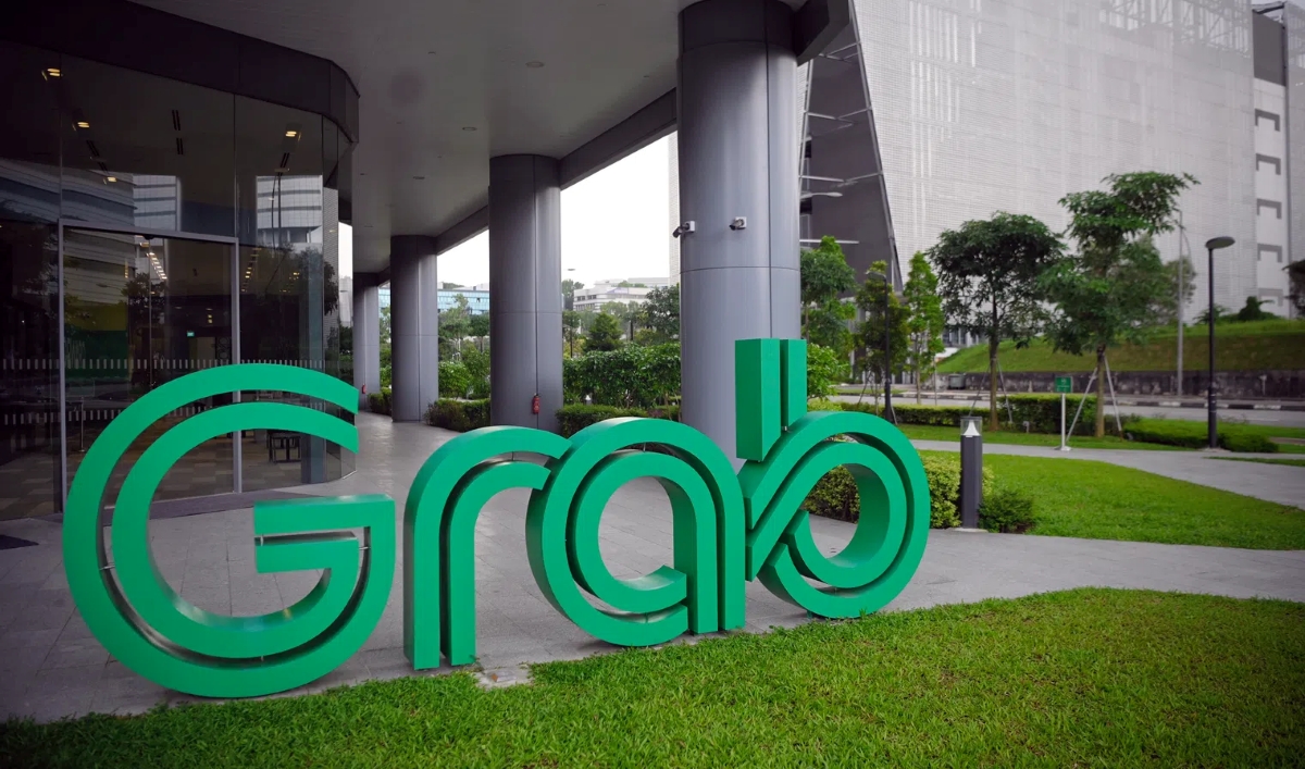 Grab headquarters exterior in Singapore, featuring the green Grab logo sculpture outside a modern office building surrounded by landscaped greenery.
