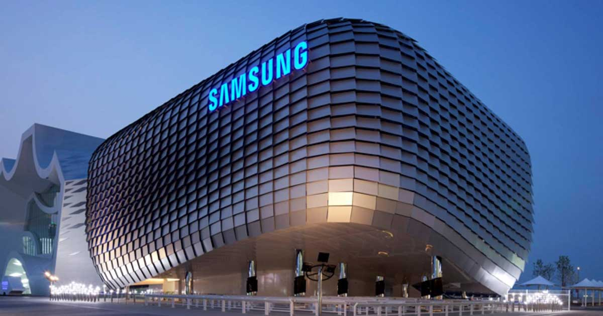 Exterior view of a modern Samsung office building with a curved metallic façade, illuminated Samsung logo, and contemporary architectural design at dusk.