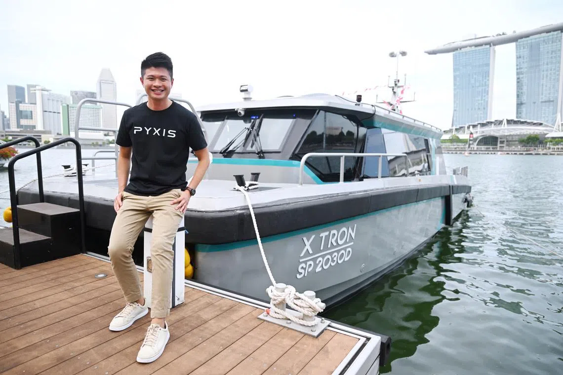 Founder standing on a dock beside an autonomous electric vessel branded X TRON SP2030D, with Marina Bay Sands and Singapore skyline in the background, highlighting maritime innovation and smart mobility.