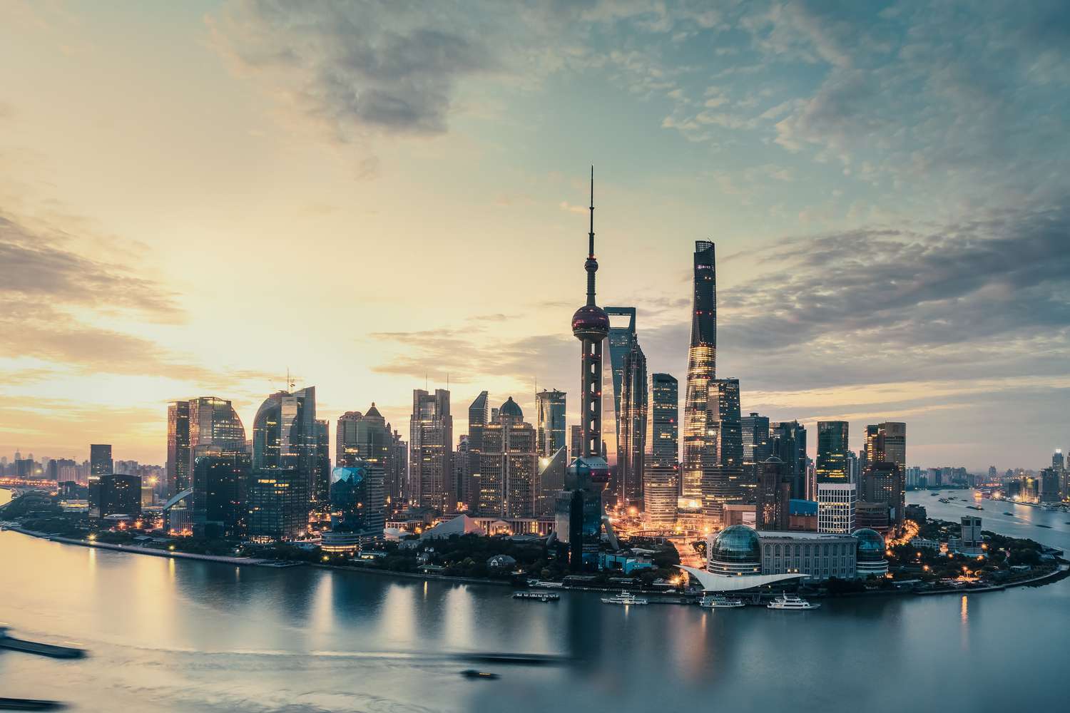 Shanghai skyline at dusk featuring the Oriental Pearl Tower, Shanghai Tower, and Lujiazui financial district along the Huangpu River, reflecting China’s global financial hub and urban transformation.