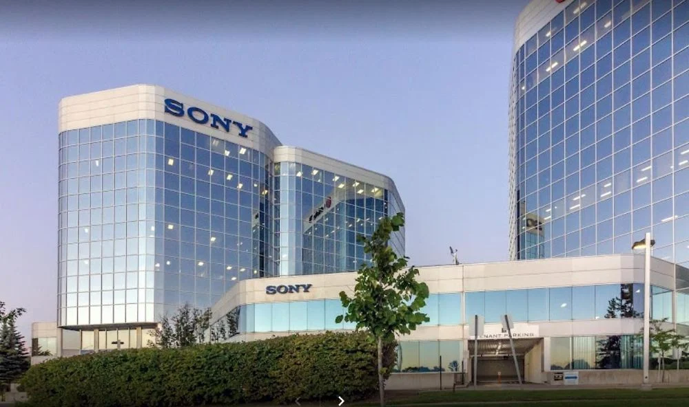 Exterior view of Sony corporate office buildings with glass façades, featuring the Sony logo on modern high-rise towers at dusk.