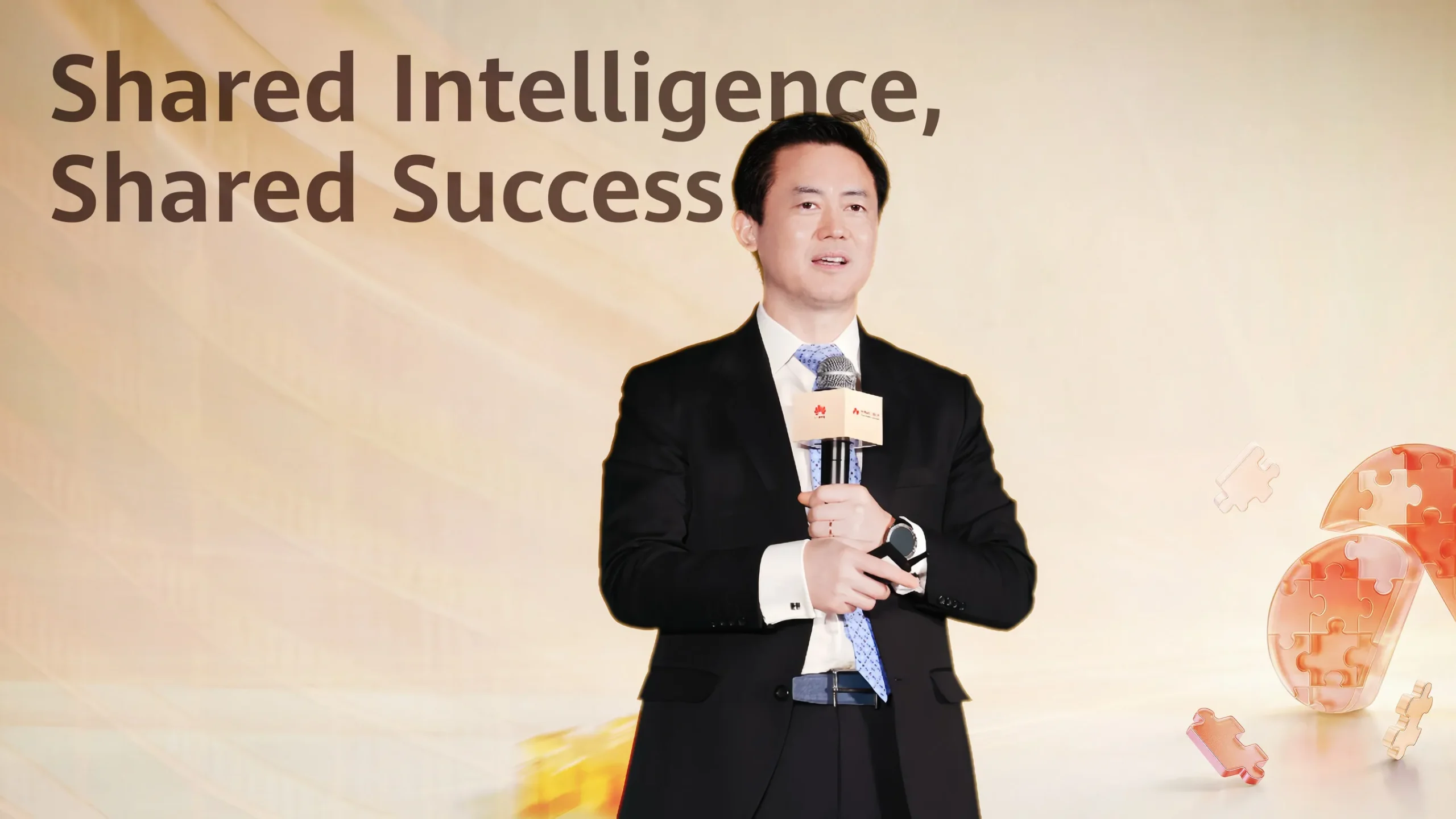 Business executive speaking on stage at a corporate leadership event, holding a microphone against a backdrop reading “Shared Intelligence, Shared Success,” highlighting collaboration, innovation strategy, and enterprise growth in Asia.