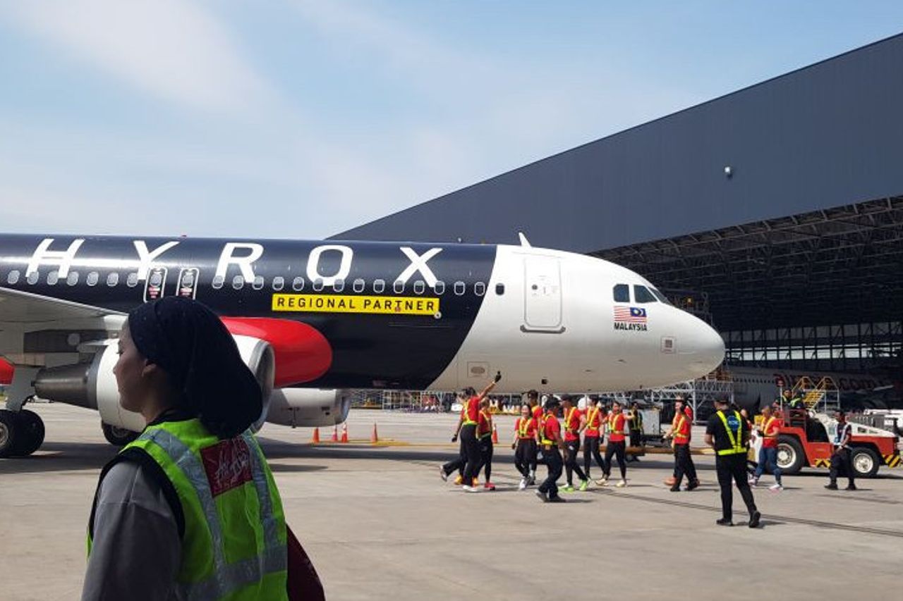 HYROX-branded aircraft on the airport tarmac in Malaysia with ground crew and logistics staff, highlighting regional aviation operations, sports event partnerships, and international travel infrastructure.