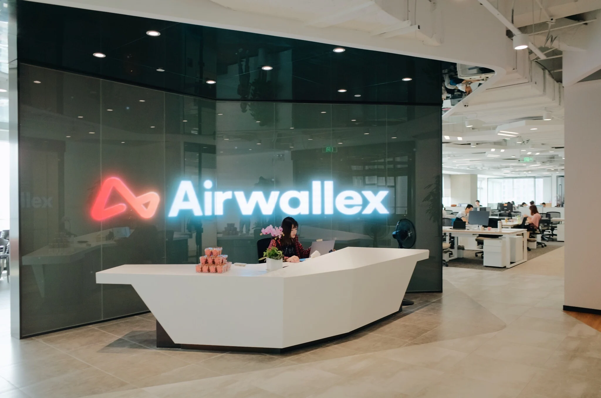 Interior of Airwallex’s modern office featuring a branded reception desk and open-plan workspace, highlighting the fintech company’s global payments platform and contemporary workplace design.