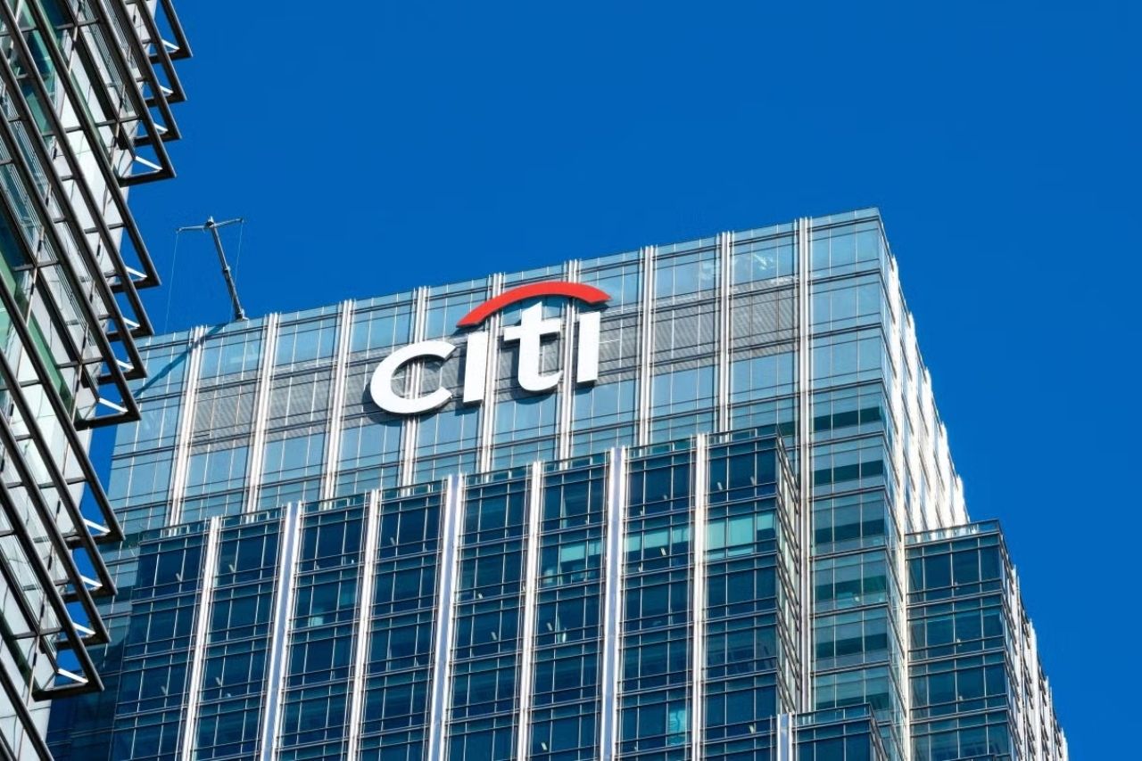 Citi logo displayed on the glass façade of a modern corporate office building against a clear blue sky, representing Citigroup’s global banking and financial services presence.
