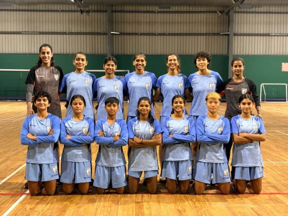 Indian women’s indoor football team posing for a group photo in light blue jerseys inside a sports hall.