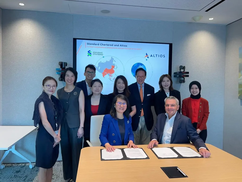Executives from Standard Chartered and Altios pose after signing a partnership agreement in a corporate meeting room, highlighting strategic collaboration, international expansion support, and cross-border business services in Asia.