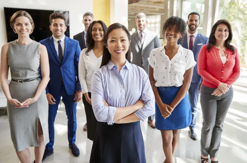 Diverse group of business professionals standing together in a modern office, with a confident female leader in the foreground, representing workplace diversity, leadership, and collaborative corporate culture.