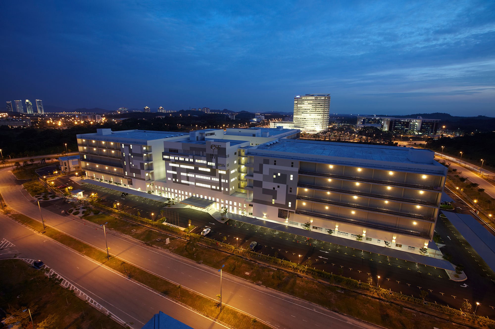 Modern commercial complex illuminated at dusk, showcasing contemporary architecture and urban infrastructure.