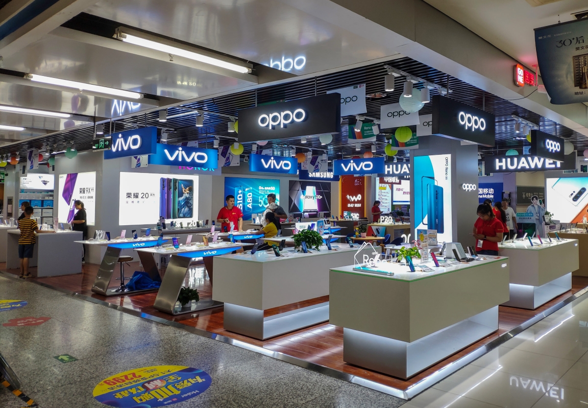 Multi-brand smartphone retail store featuring OPPO, vivo, and Huawei display counters with customers browsing devices.