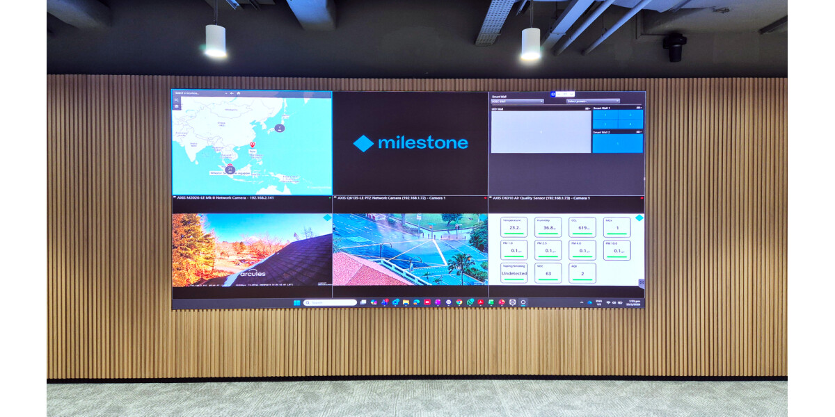 Milestone video surveillance dashboard displaying live monitoring screens, smart analytics data, and regional network overview in control room setting.