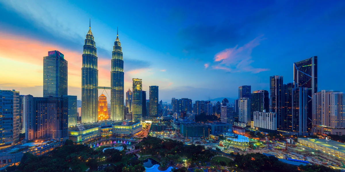 Kuala Lumpur skyline at sunset featuring Petronas Twin Towers and illuminated cityscape, highlighting Malaysia’s financial and business district.