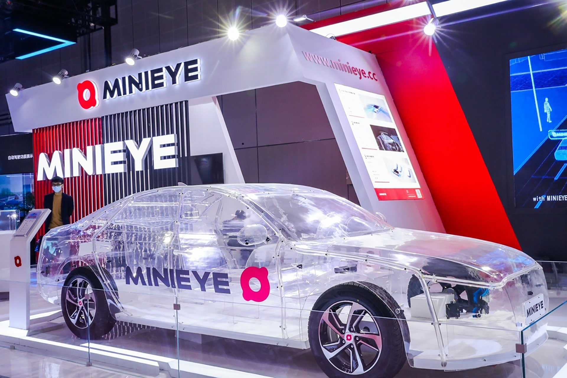 MINIEYE autonomous driving technology showcase featuring transparent concept car at automotive AI and smart mobility exhibition booth.