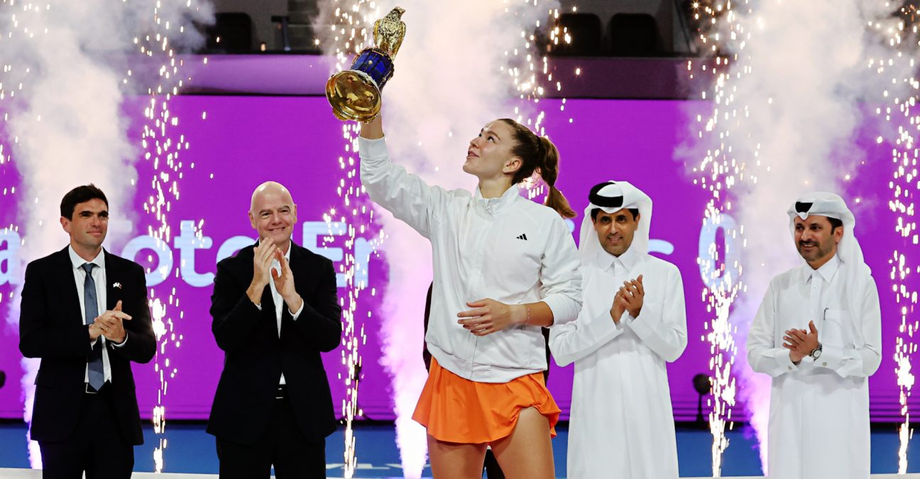 Women’s tennis champion lifts trophy during awards ceremony with fireworks and officials on stage at Qatar Open tournament.