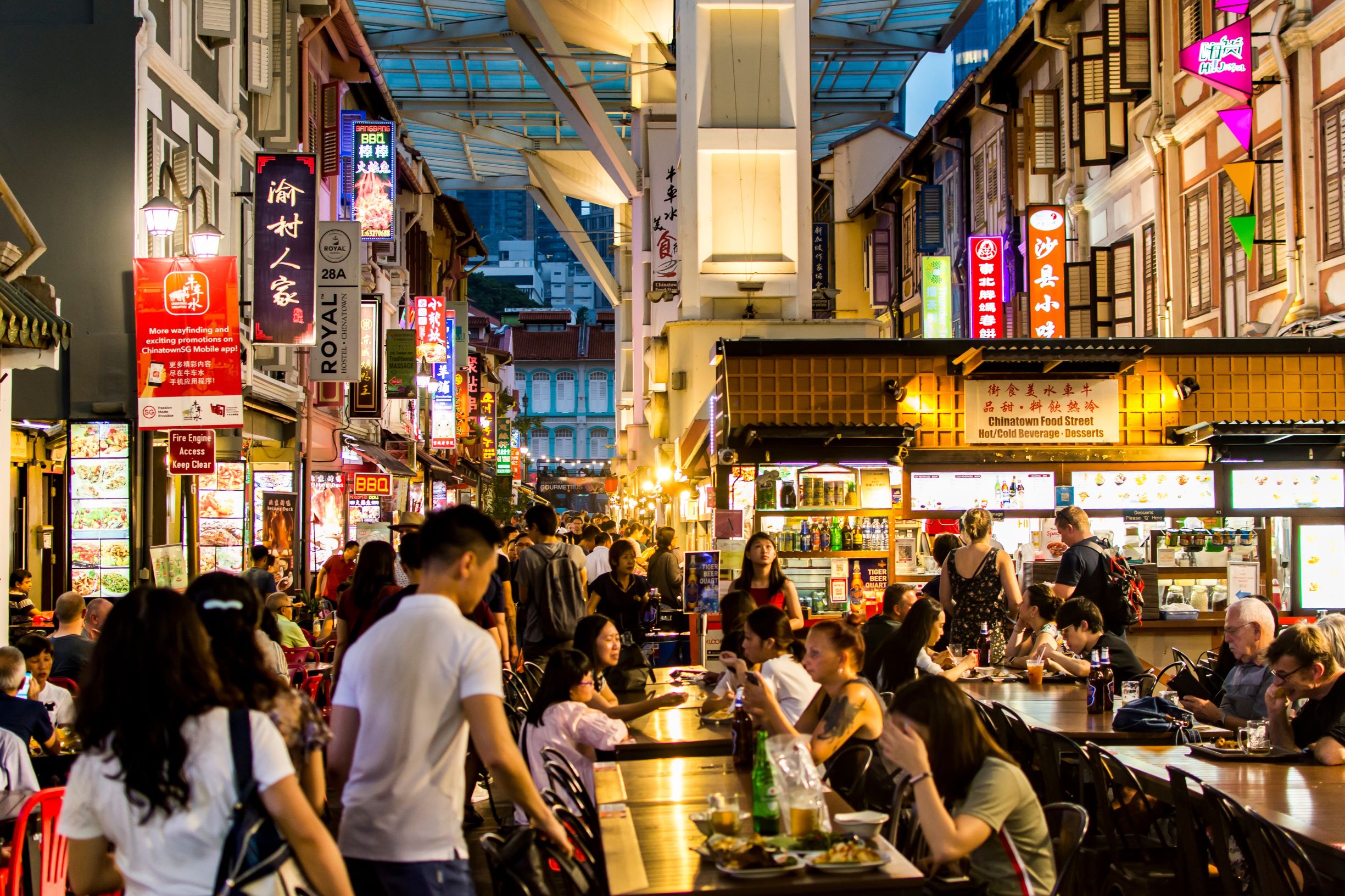 Crowded Chinatown food street at night with diners and street-side eateries under colorful neon signs, capturing Singapore’s vibrant nightlife, hawker culture, and urban tourism scene.