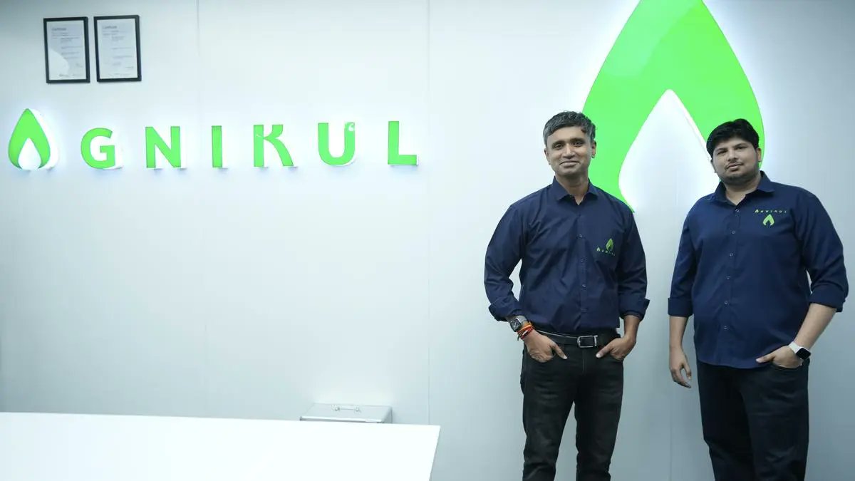 Gnìkul founders standing at the company’s office headquarters beside the illuminated GNIKUL logo, highlighting innovation in sustainable agritech solutions.