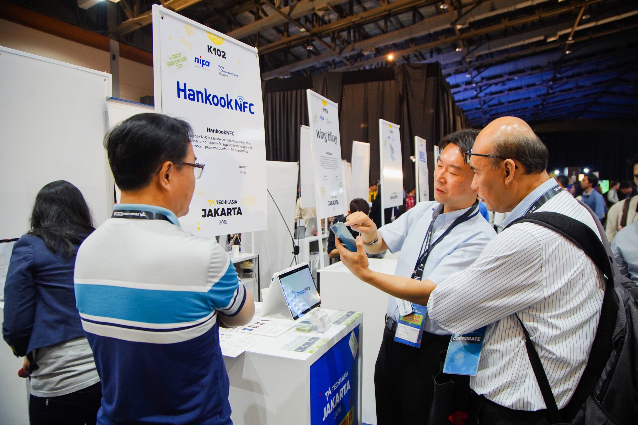 Startup founders and attendees discussing a mobile payment solution at the HankookNFC booth during Tech in Asia Jakarta, highlighting fintech innovation, NFC technology, and startup networking in Southeast Asia.
