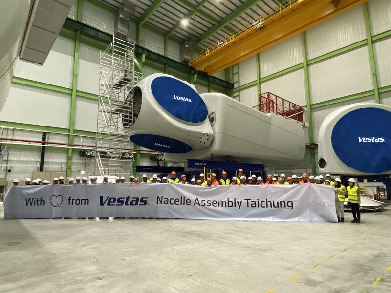 Vestas wind turbine nacelle assembly facility in Taichung with workers posing in front of large turbine components inside a factory.