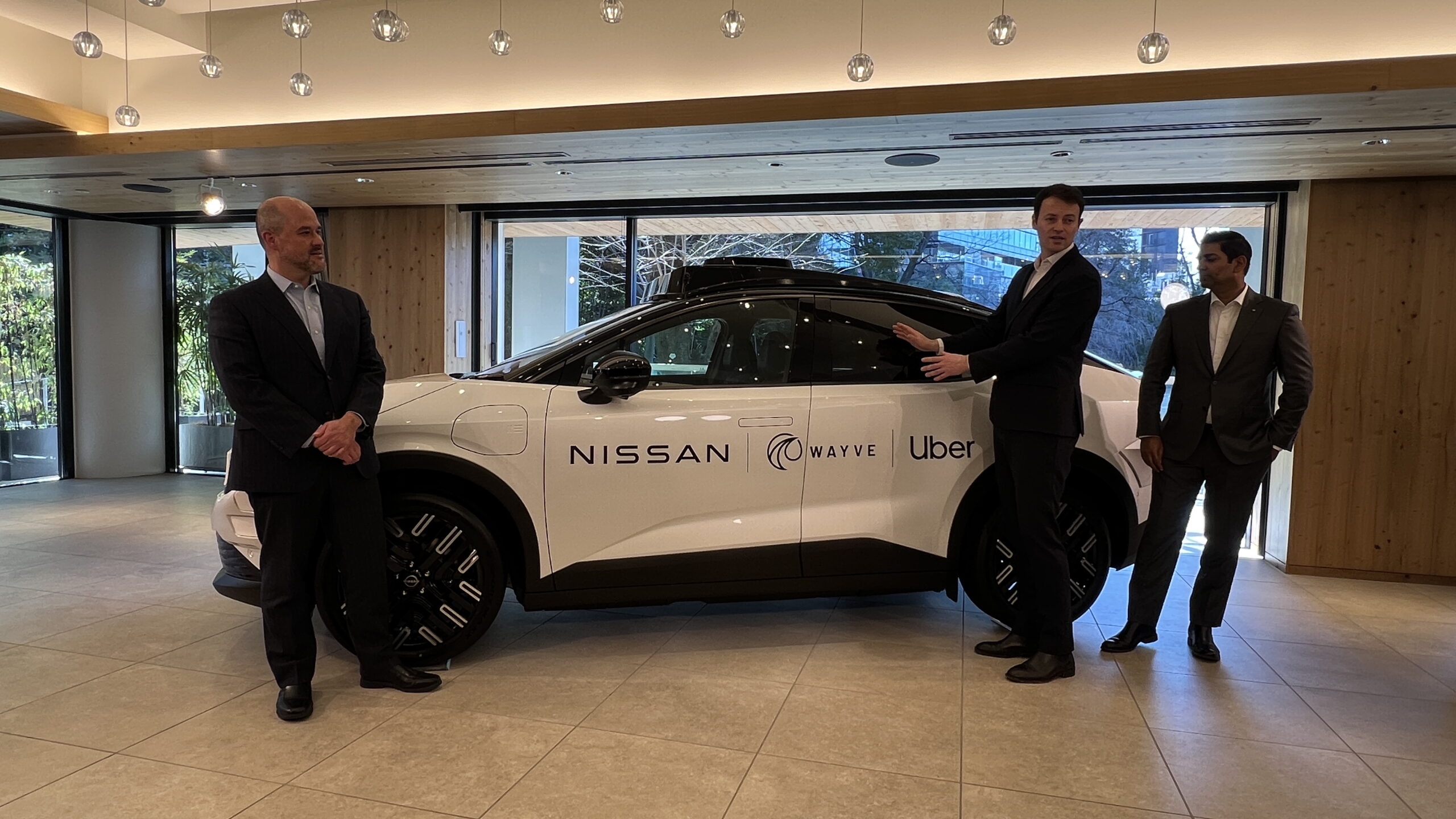 Nissan autonomous vehicle showcased with executives at a corporate event, highlighting self-driving technology and mobility innovation partnership.