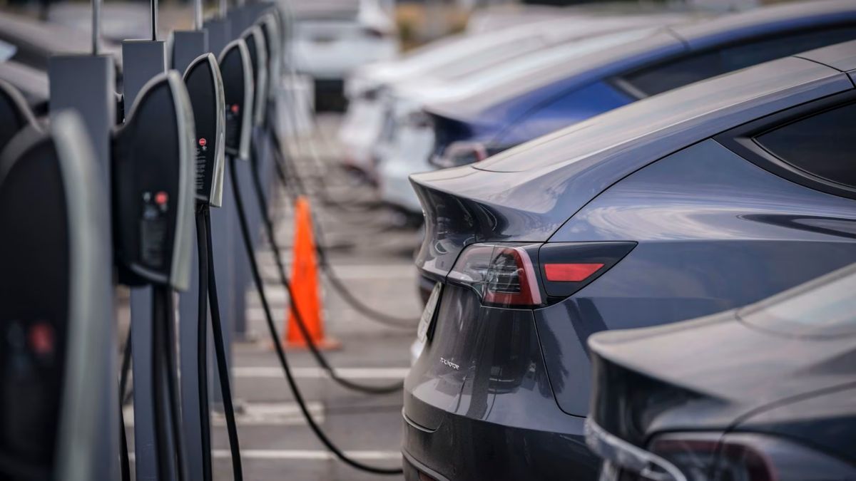 Electric vehicles charging at a public EV charging station, showing multiple cars plugged into fast chargers in a modern urban parking area.