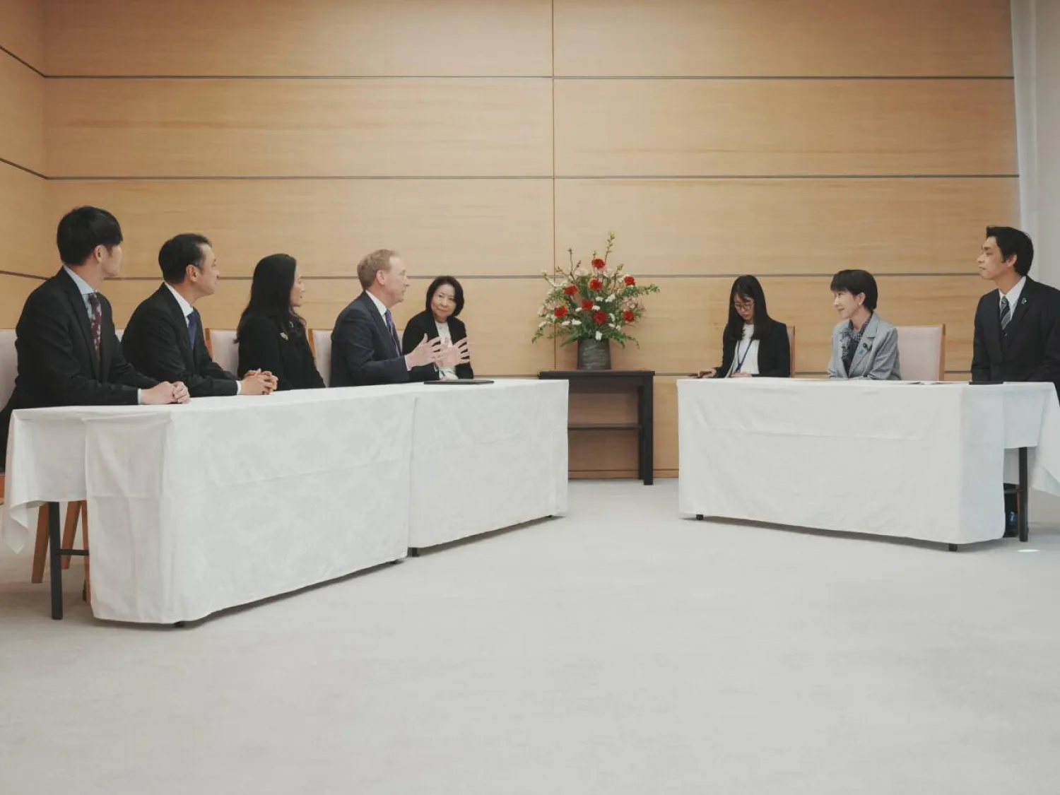 Business meeting with executives seated across tables in formal discussion, representing corporate negotiations, leadership dialogue, and international business collaboration.