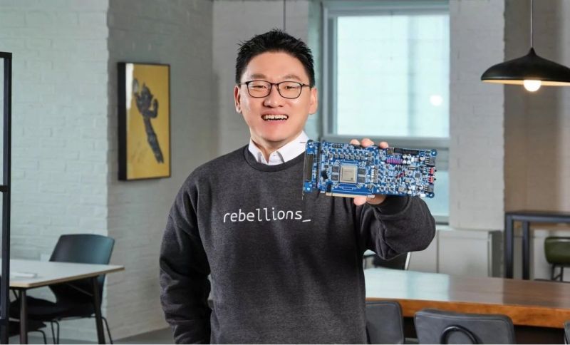 Tech entrepreneur holding a semiconductor chip board inside an office, showcasing hardware innovation from Rebellions AI.