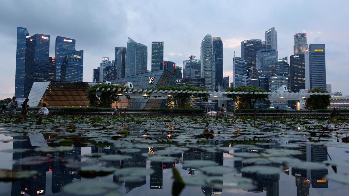 Singapore skyline at Marina Bay with luxury retail pavilion and lily pond in foreground, showcasing urban architecture, financial district towers, and waterfront cityscape at dusk.
