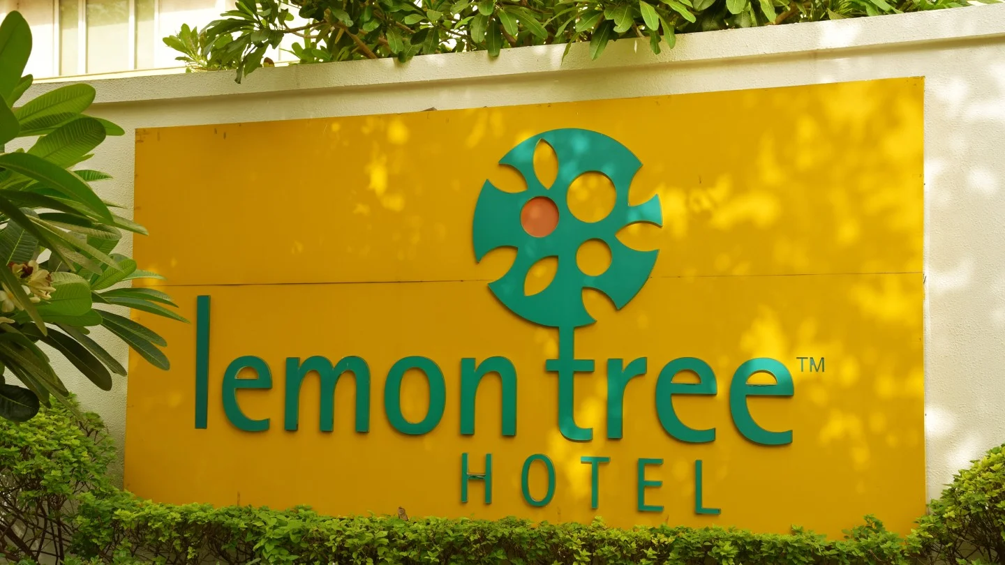 Lemon Tree Hotel signage on exterior wall surrounded by greenery, representing India’s hospitality sector and mid-market hotel brand presence.