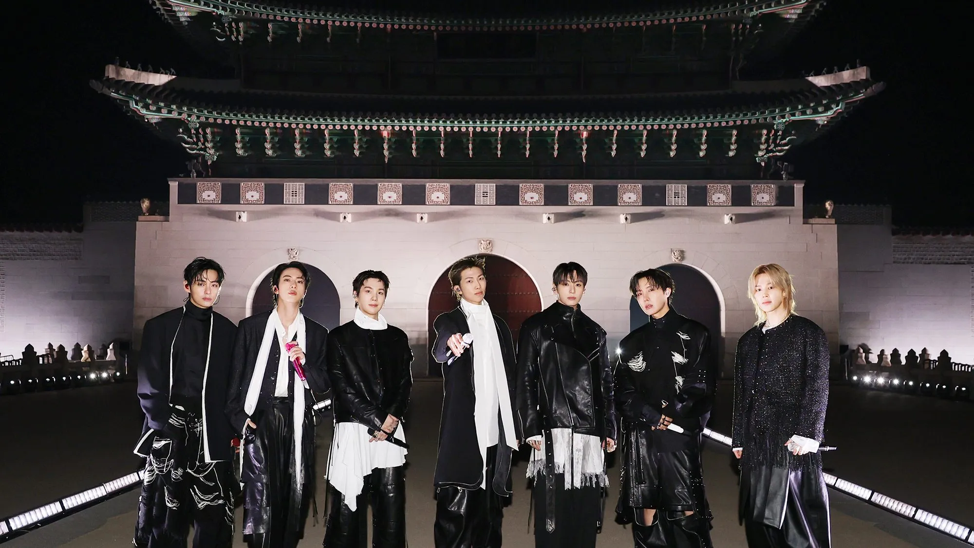 K-pop group BTS posing in front of historic Korean palace at night, blending modern music culture with traditional architecture and global entertainment influence.