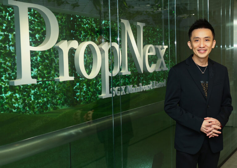 Kelvin Fong, CEO of PropNex Realty, standing in a modern office beside a glass wall with the PropNex logo, smiling in a black suit.