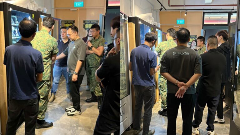 Adrian Soh explaining a smart vending machine to a group including servicemen and staff during a live demonstration.