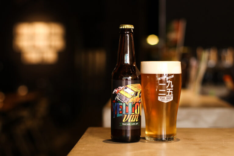 Bottle and glass of Yellow Van pale ale by The 1925 Brewing Co. displayed on a bar counter.