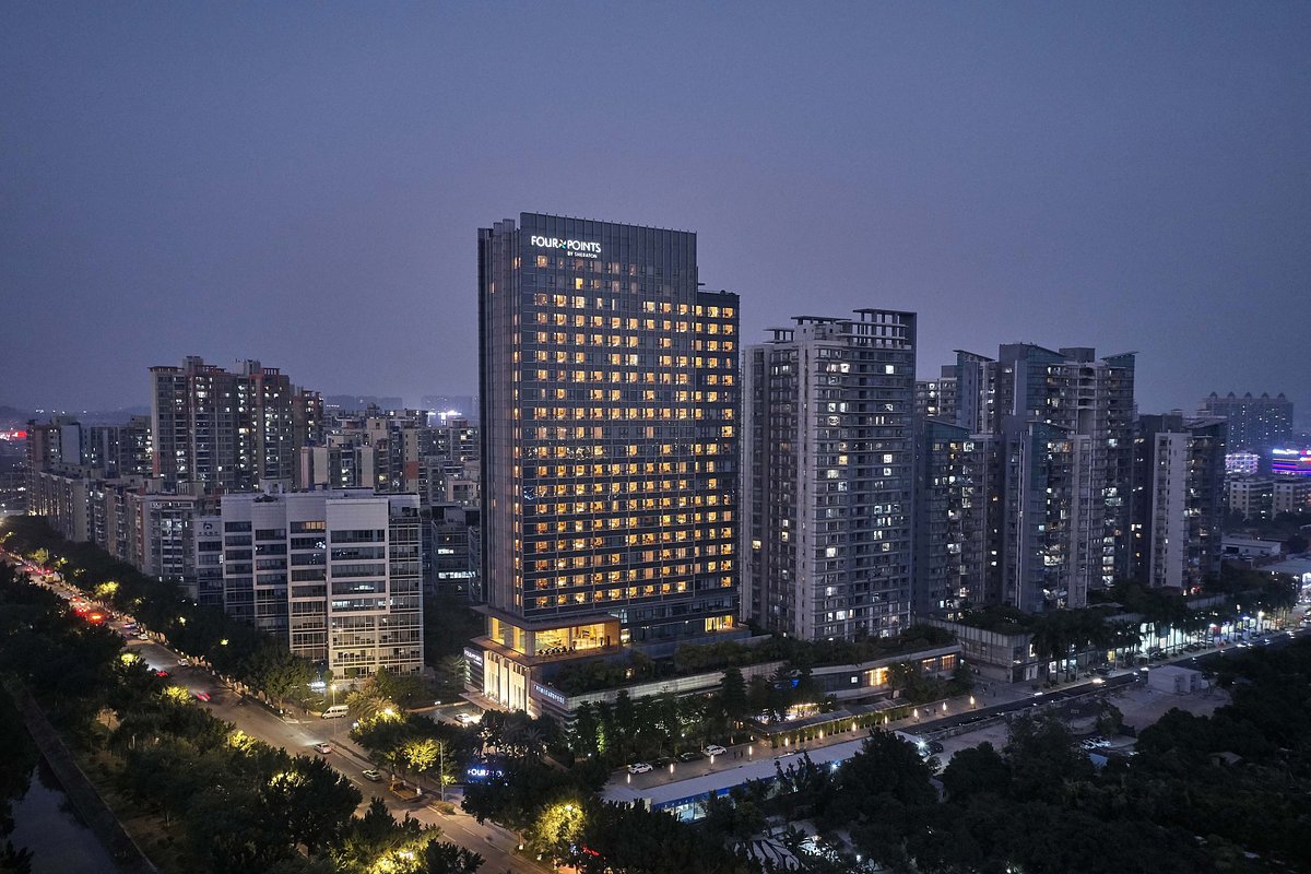 Four Points by Sheraton hotel tower illuminated at night in a modern urban district, surrounded by high-rise residential buildings and city lights in Asia.