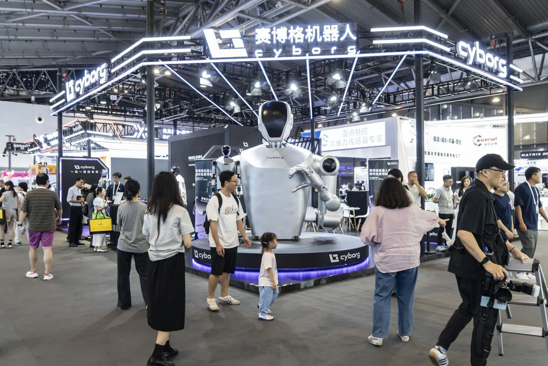 Visitors explore humanoid robot display at Cyborg Robotics booth during a technology expo, showcasing AI-powered robotics and automation innovation in Asia.