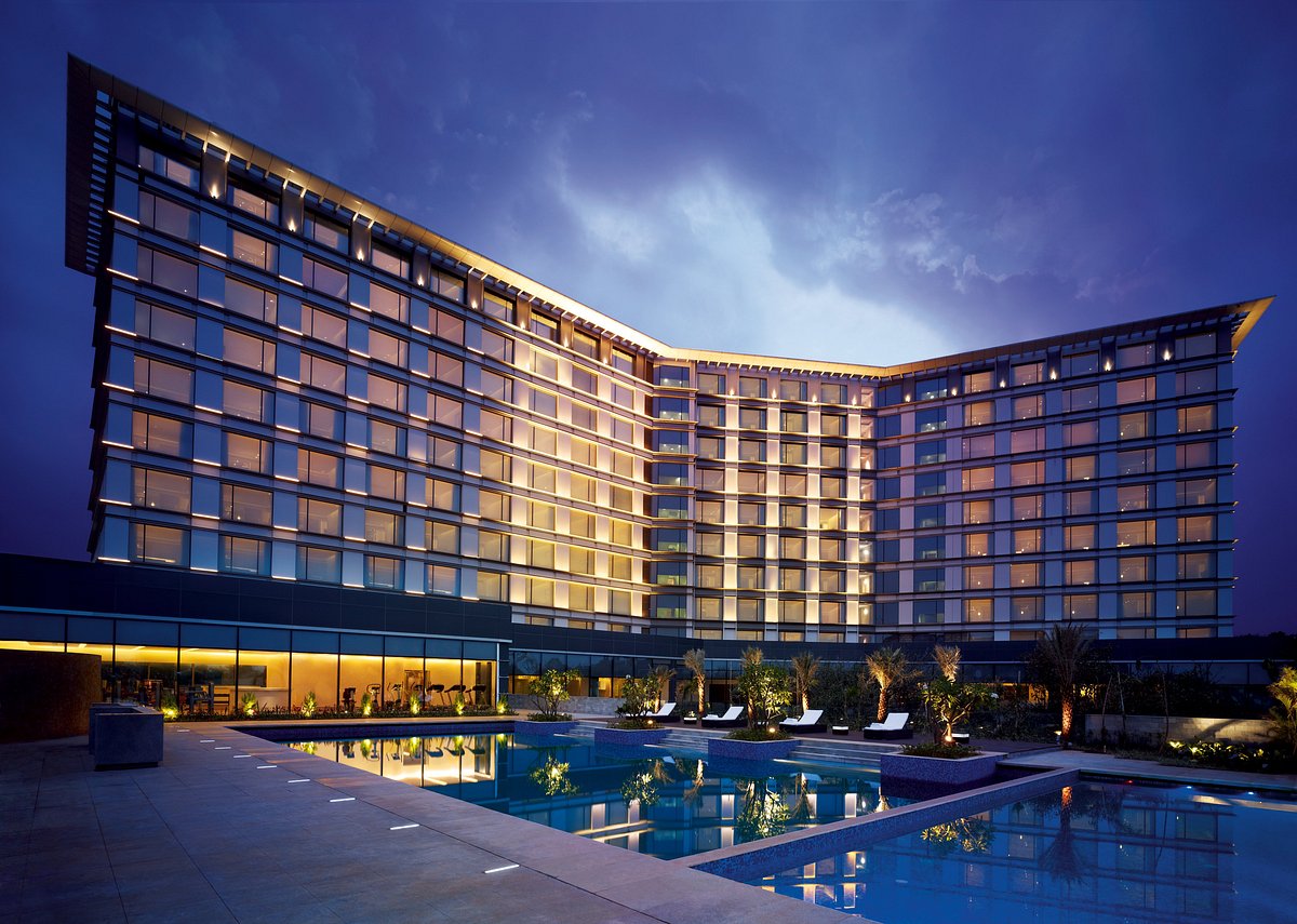 Top 10 Asian Luxury modern hotel exterior with illuminated glass architecture and outdoor swimming pool at dusk, showcasing premium hospitality and urban resort design in Asia.