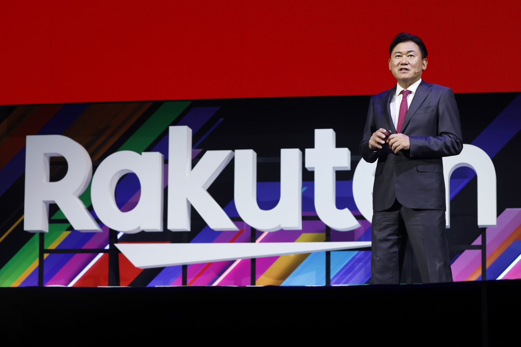Rakuten executive speaking on stage at a corporate technology event, highlighting the Japanese company’s digital services, e-commerce, and innovation strategy.
